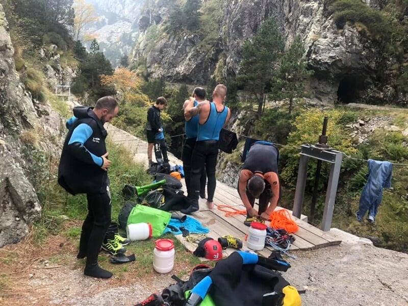 Personnes en tenue de canyoning préparant leur matériel au bord d'un chemin rocheux en montagne.