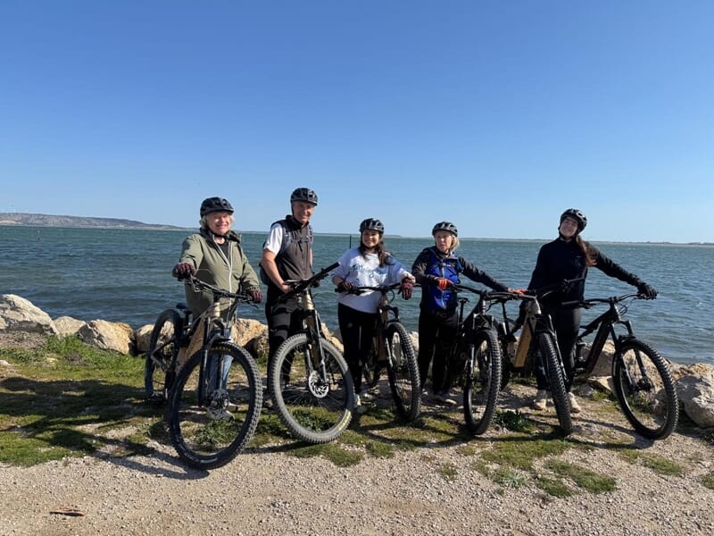 Groupe de personne de personnes en VTT électrique en ligne posant devant une étendue d'eau