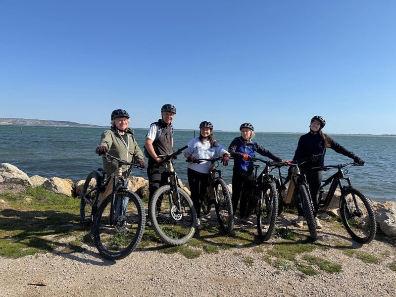 Groupe de personne de personnes en VTT électrique en ligne posant devant une étendue d'eau