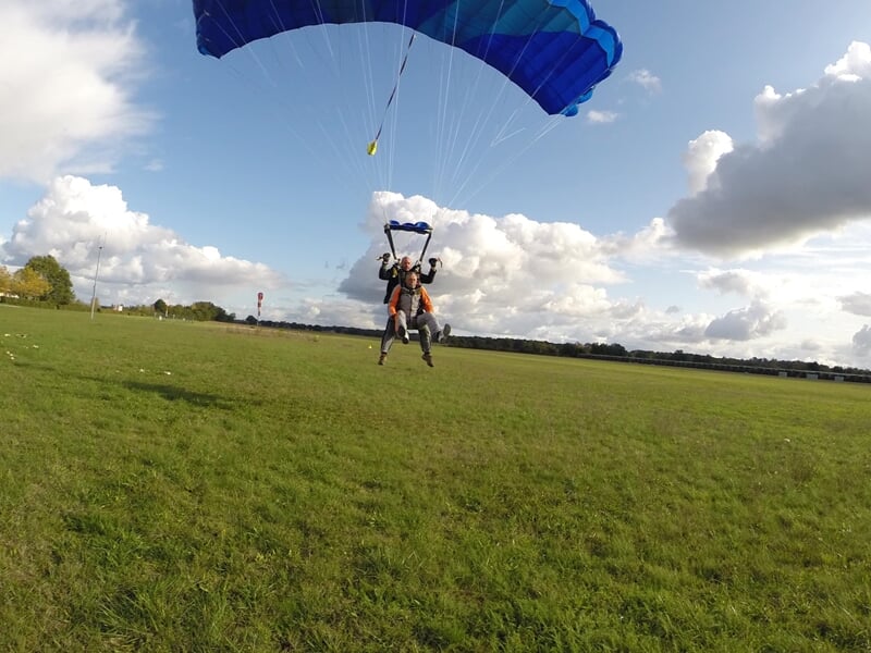 Saut en parachute, personne en chute libre avec ciel bleu et nuages en arrière-plan.