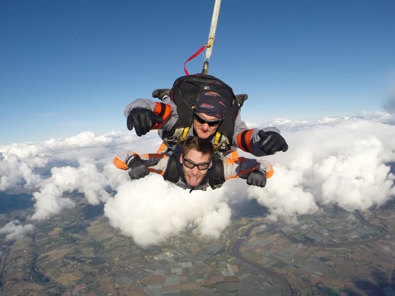 Saut en parachute tandem au-dessus d'un aéroport, deux personnes en chute libre.