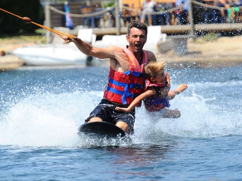 Un homme et un enfant en kneeboard, vêtus de gilets de sauvetage rouges et bleus