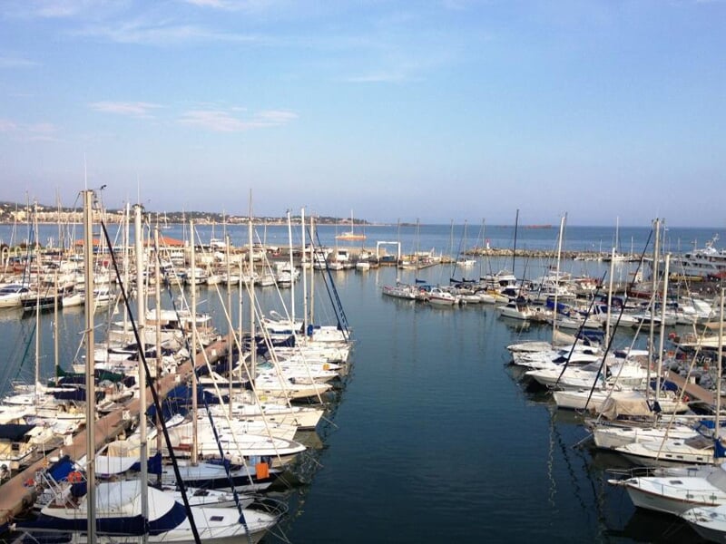 Vue panoramique du port de plaisance avec de nombreux bateaux amarrés sous un ciel bleu clair.