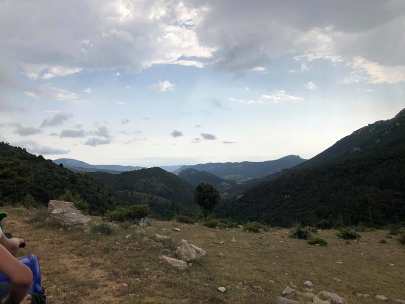 Paysage de montagne avec ciel nuageux et vallée verdoyante, vue depuis un sentier de randonnée en quad.