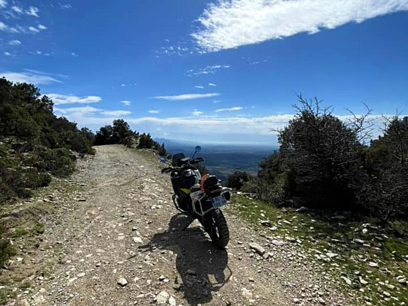une moto sur un sentier en altitude devant un bel horizon