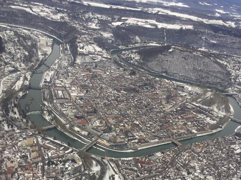 Photographie aérienne d'une ville enneigée encerclée par une rivière avec plusieurs ponts reliant ses quartiers.