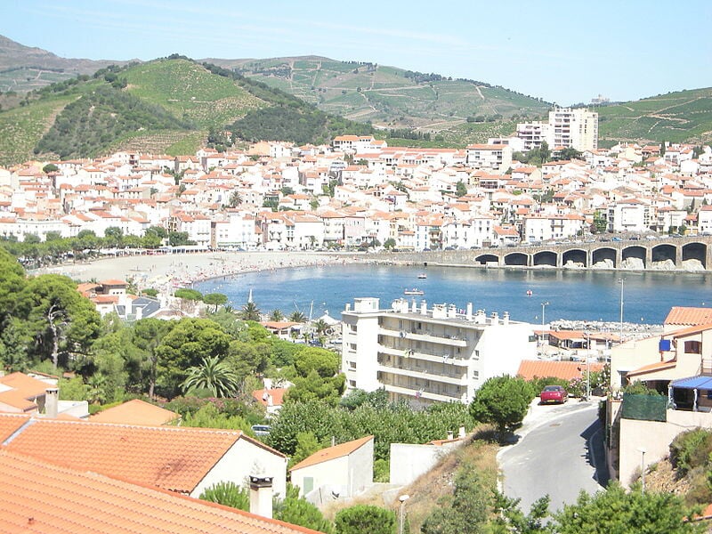 Vue d'une ville côtière avec des toits rouges et une baie en forme de croissant.