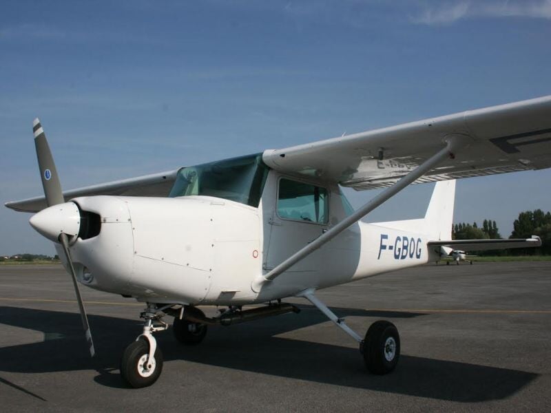 Petit avion blanc immatriculé F-GBDG stationné sur une piste d'aéroport par temps clair et ciel bleu.