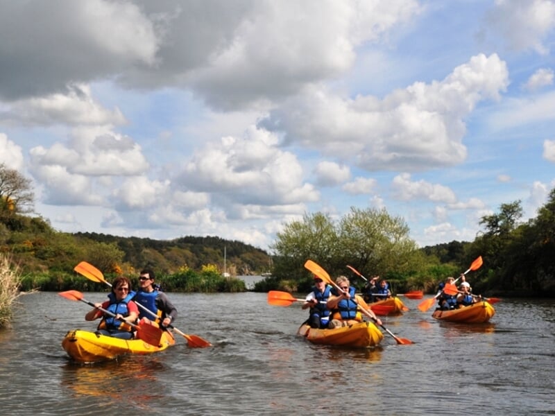 Rangée de kayaks rouges et jaunes empilés sur un véhicule près d'un quai avec un homme debout.