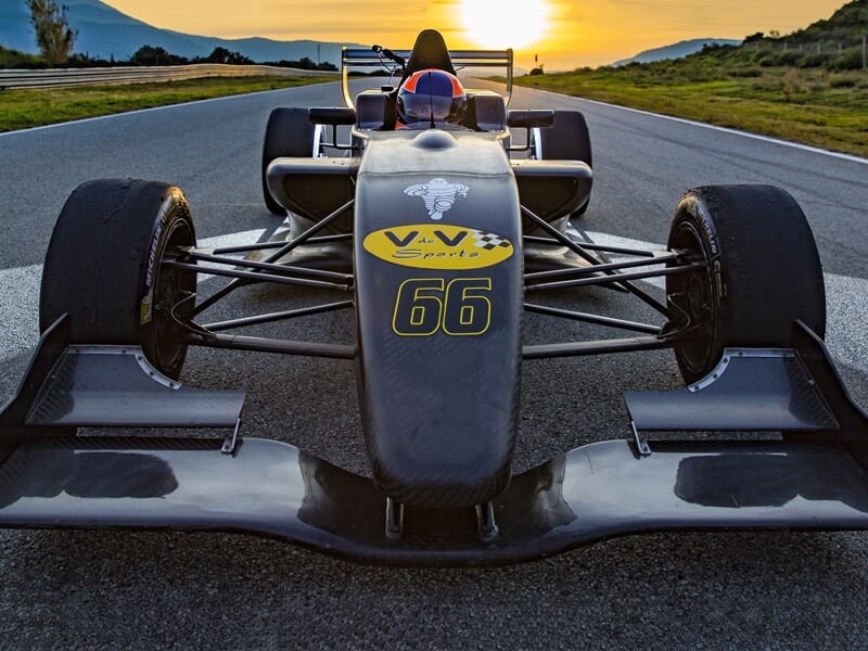 Formule Renault noire vue de face sur la piste au coucher du soleil avec le numéro 66 sur le capot.