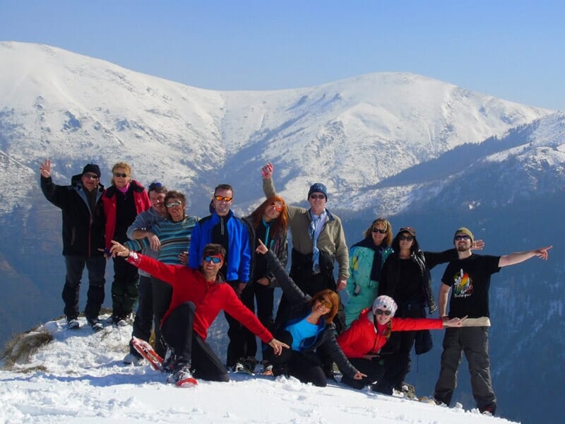des randonneurs en tenue de ski posent devant une montagne enneigée