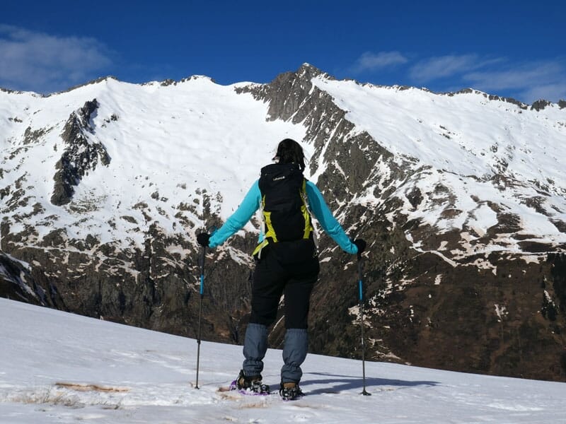 Randonneurs suivant une trace dans la neige en direction d'une montagne avec un ciel bleu au-dessus