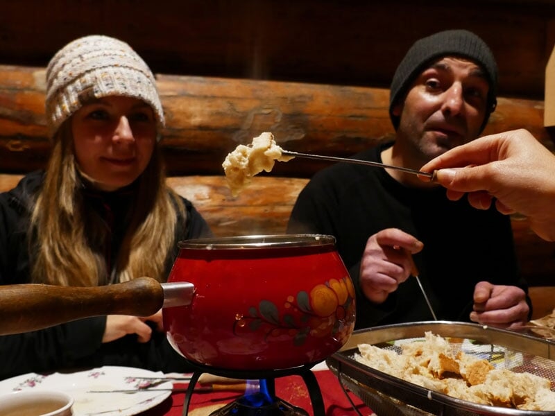 Deux personnes profitant d'une fondue au fromage dans un chalet de montagne, ambiance cosy