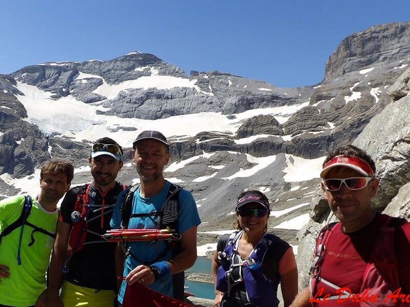 Groupe de randonneurs posant devant un paysage de montagnes enneigées.