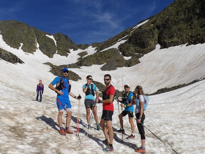 Groupe de coureurs posant sur un champ de neige entre des montagnes rocheuses.