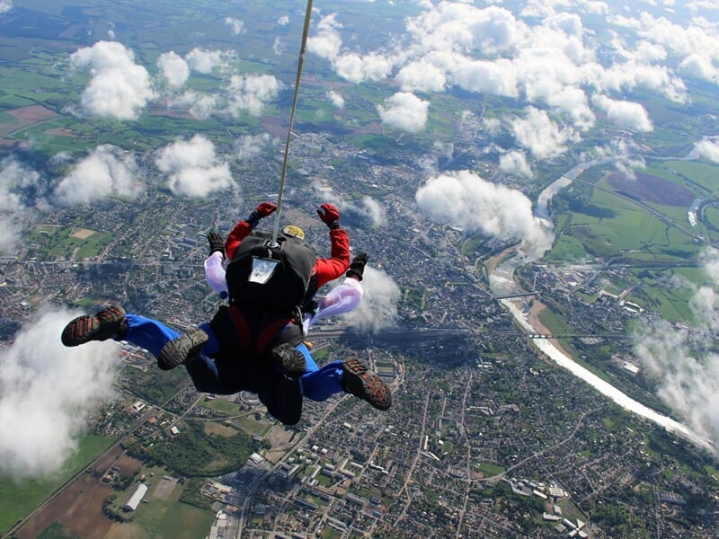 Saut en parachute en tandem au-dessus de Nevers, vue aérienne sur la campagne et les nuages blancs dans le ciel.