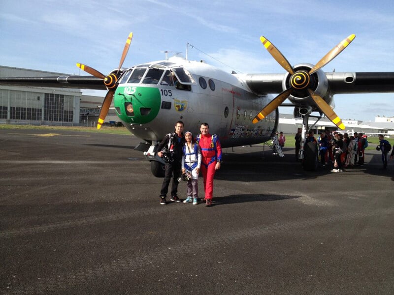 Groupe de personnes posant devant un avion après un saut en parachute