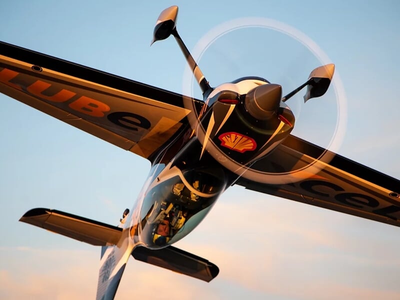 Avion de voltige noir et blanc avec inscription jaune 'LUB' sur l'aile, posé sur une piste.