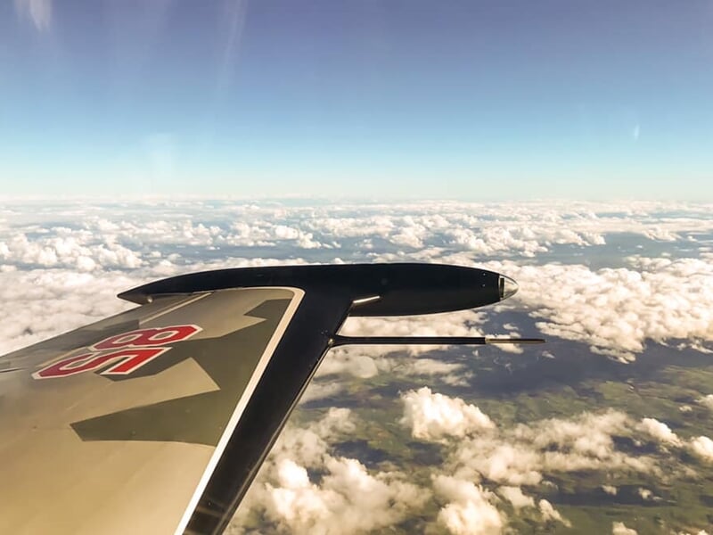 vue du ciel et d'une mer de nuages depuis le cockpit d'un avion de chasse avec l'aile droite au premier plan