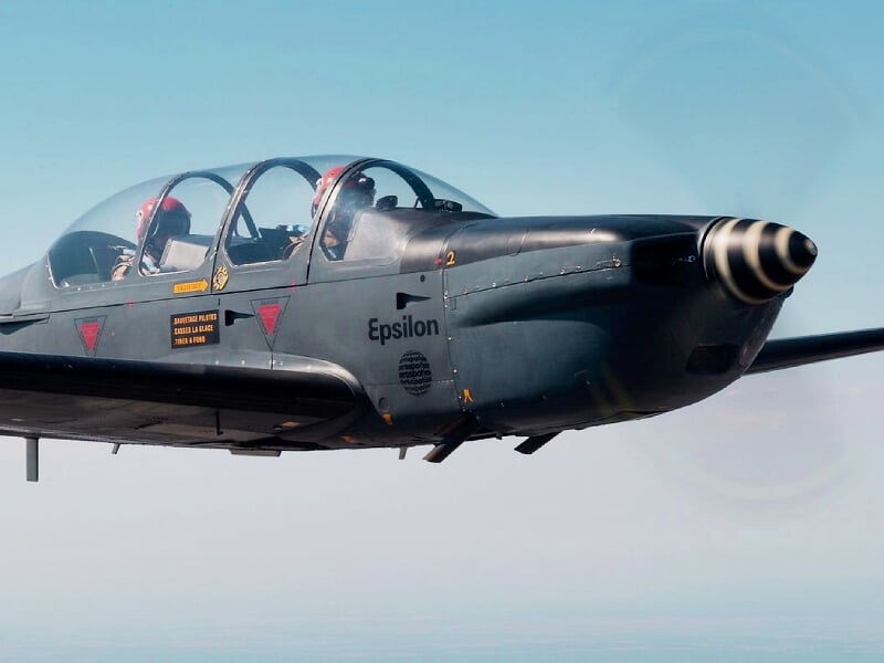 Avion de chasse camouflé gris avec éclairage dramatique dans un hangar sombre.