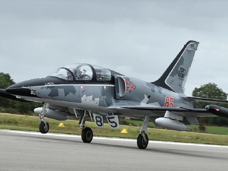 Avion de chasse gris avec camouflage en train de rouler sur une piste d'aéroport.