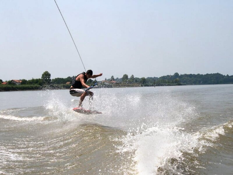 Personne pratiquant le wakeboard sur un plan d'eau, en train de sauter et éclabousser l'eau.