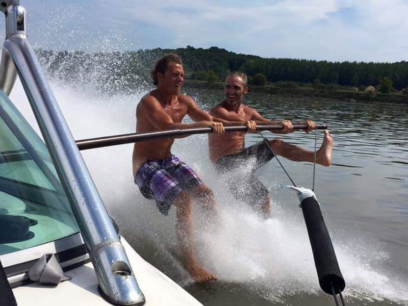 Deux hommes s'amusant sur un bateau, éclaboussant l'eau en riant et profitant du moment.