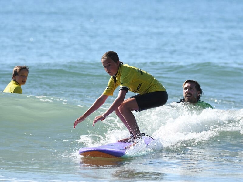 une enfant se lève sur la planche et surfe une vague
