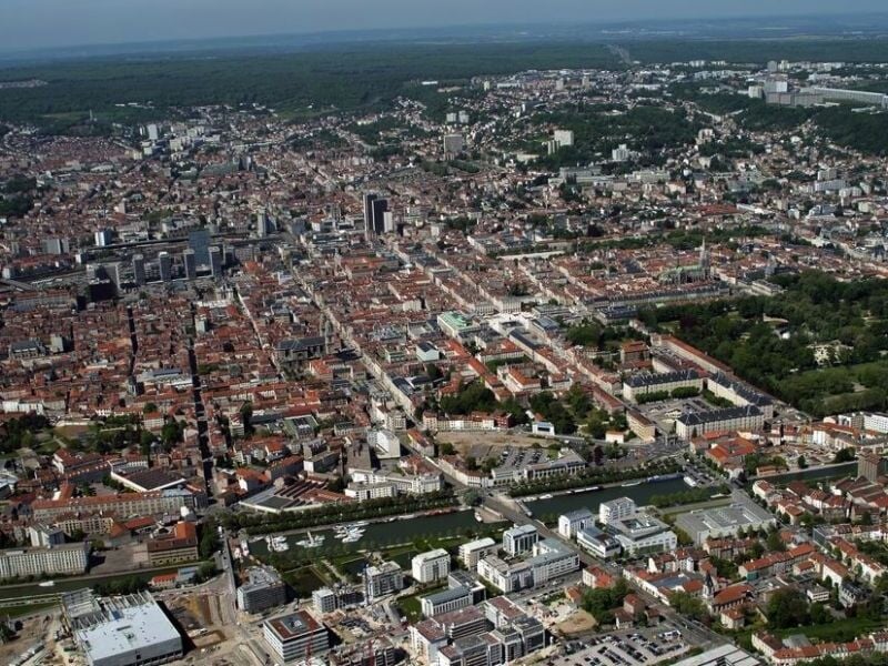 Vue aérienne d'une grande ville avec des bâtiments, rues et rivière, prise depuis un avion.