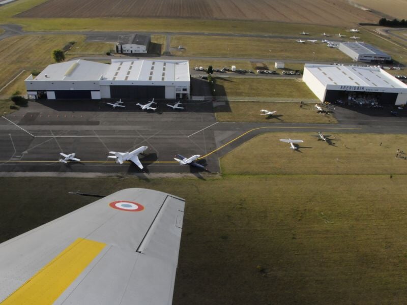 Vue aérienne d'un aérodrome avec plusieurs avions stationnés et piste visible depuis un avion.