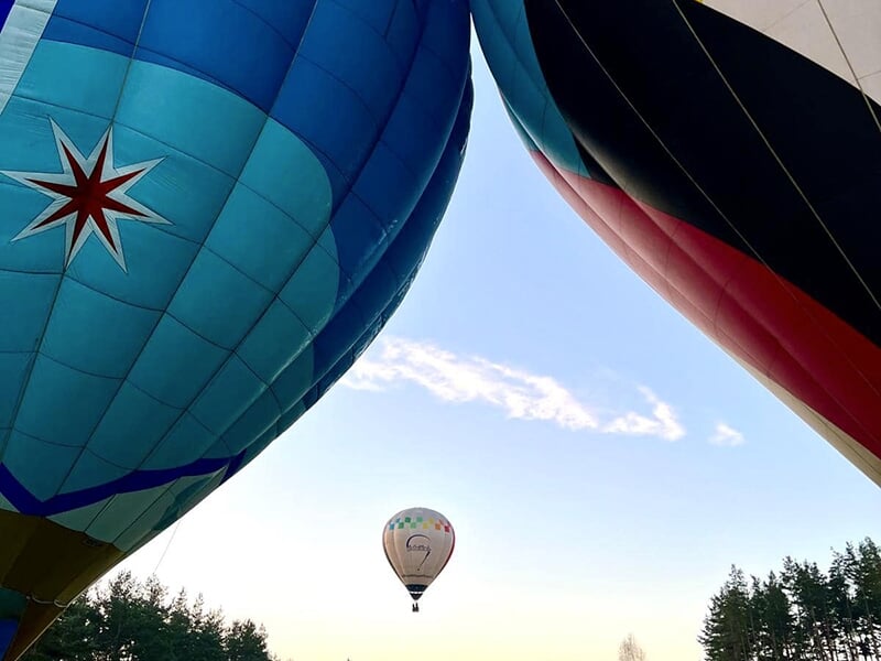 Deux montgolfières colorées en gros plan avec une troisième montgolfière en arrière-plan dans le ciel.