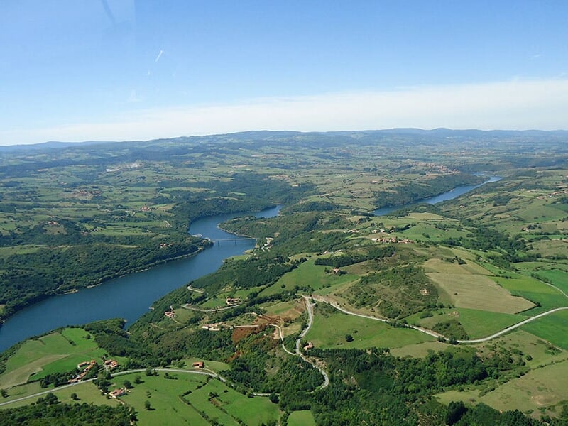 Paysage vu du ciel avec une rivière sinueuse traversant des collines verdoyantes et des champs agricoles.