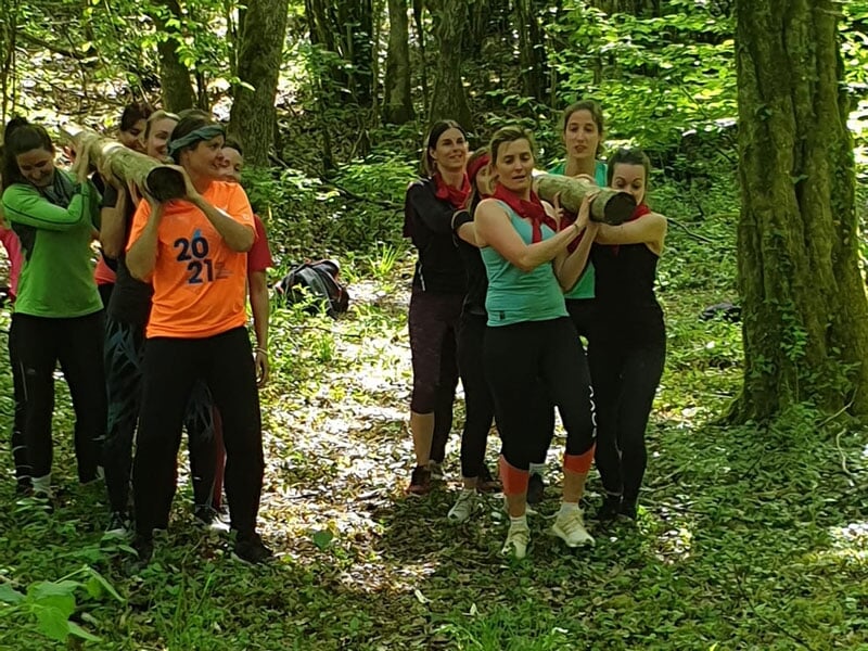 des femmes font une course insolite dans la nature en transportant un rondin de bois en équipe