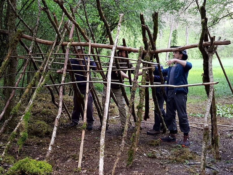 deux personnes construisent le squelette d'un abri de survie en bois