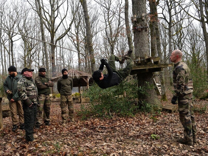un homme traverse en cochon pendu à la corde lors d'un stage commando