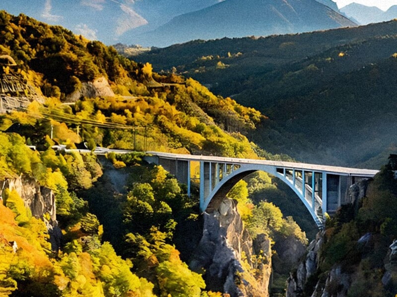 Pont de Ponsonnas, site emblématique pour le saut à l'élastique, enjambant une vallée entourée de montagnes aux couleurs automnales. La lumière dorée met en valeur ce lieu prisé pour les sports extrêm