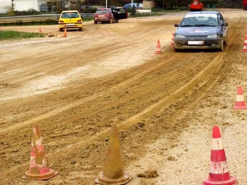 Voiture grise sur une piste de terre entourée de cônes de signalisation