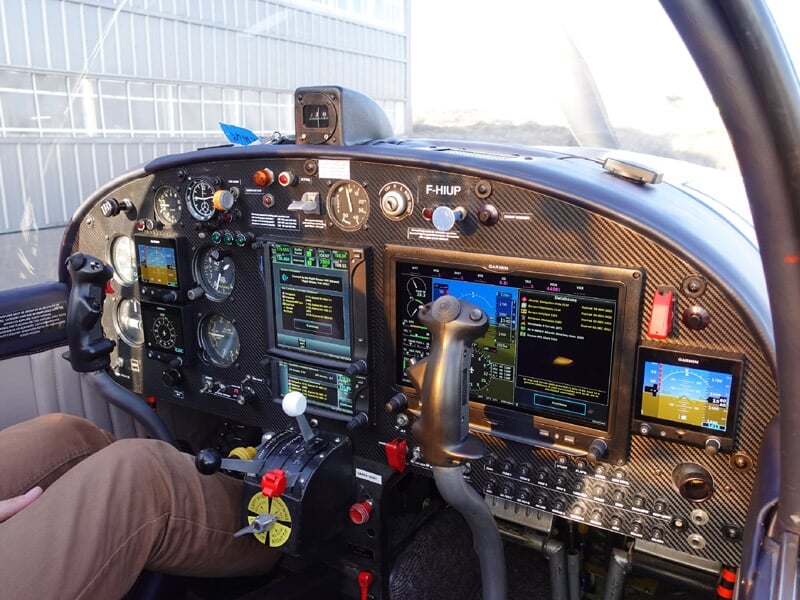 Cockpit d'un avion de voltige avec instruments de pilotage et commandes visibles, pilote assis.