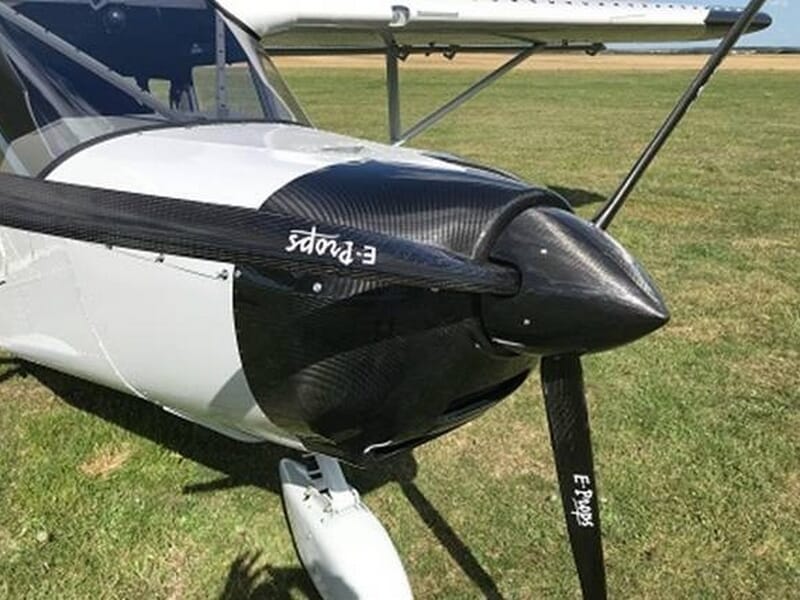 Gros plan sur l'hélice noire d'un avion ULM blanc stationné sur une piste d'herbe verte initiation ULM près de Fontainebleau.