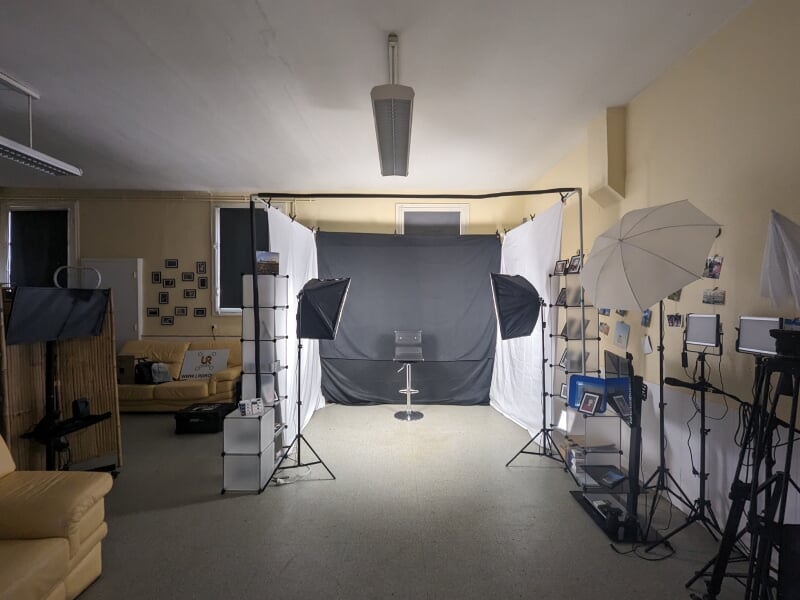Un studio de photographie avec des équipements professionnels, incluant des éclairages, des fonds noirs et blancs, et des supports pour accessoires. L'ambiance est propice à une séance photo.