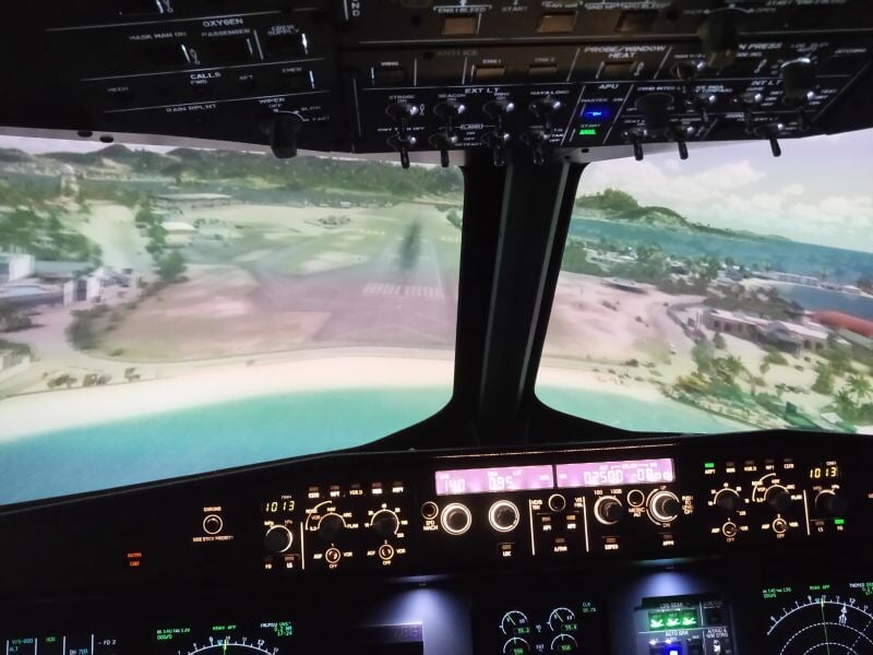 Cockpit d'un simulateur de vol d'avion avec vue sur une piste d'atterrissage et paysage côtier virtuel