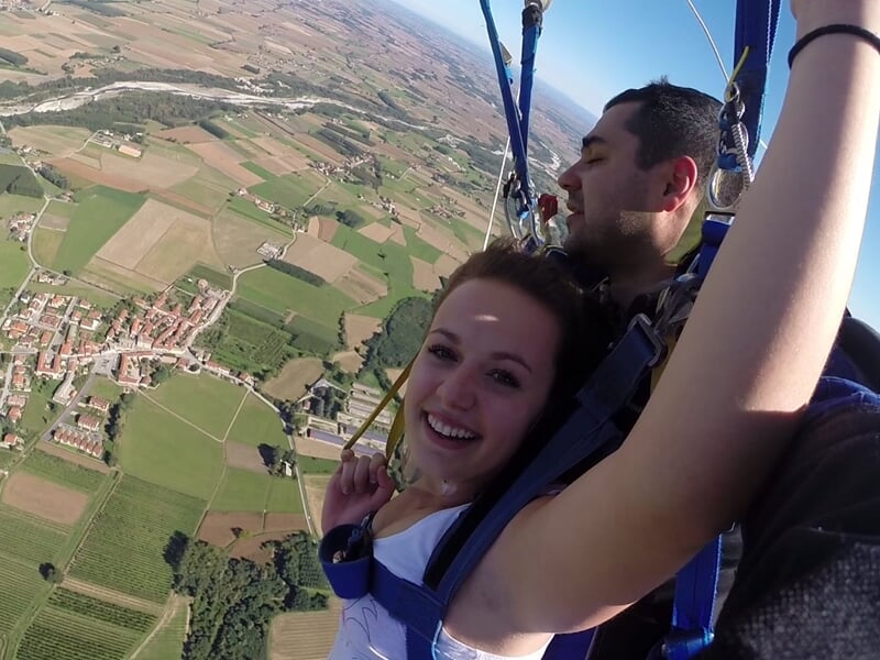 une femme et un instructeur de saut en parachute descendent en douceur sous la voile du parachute