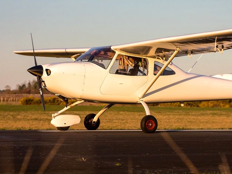 un avion ulm multiaxes à l'arrêt sur une piste de décollage au crépuscule