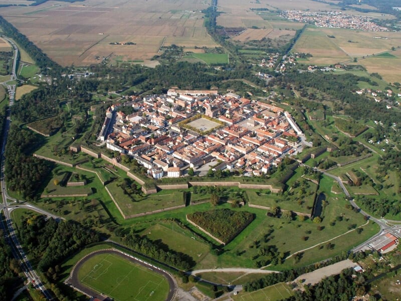 Vue aérienne d'une ville fortifiée avec des remparts en forme d'étoile et des bâtiments anciens.