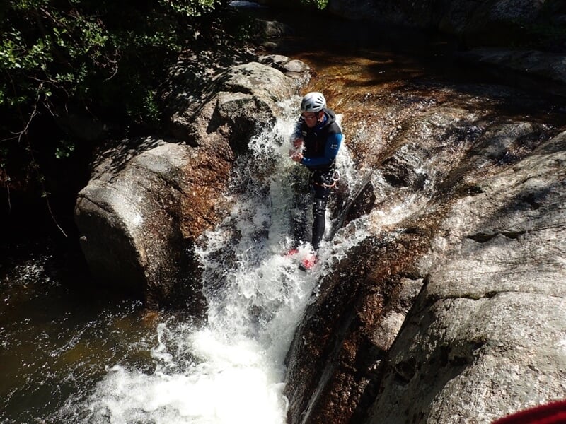Groupe de personnes en combinaison posant souriants devant une cascade dans un canyon rocheux.