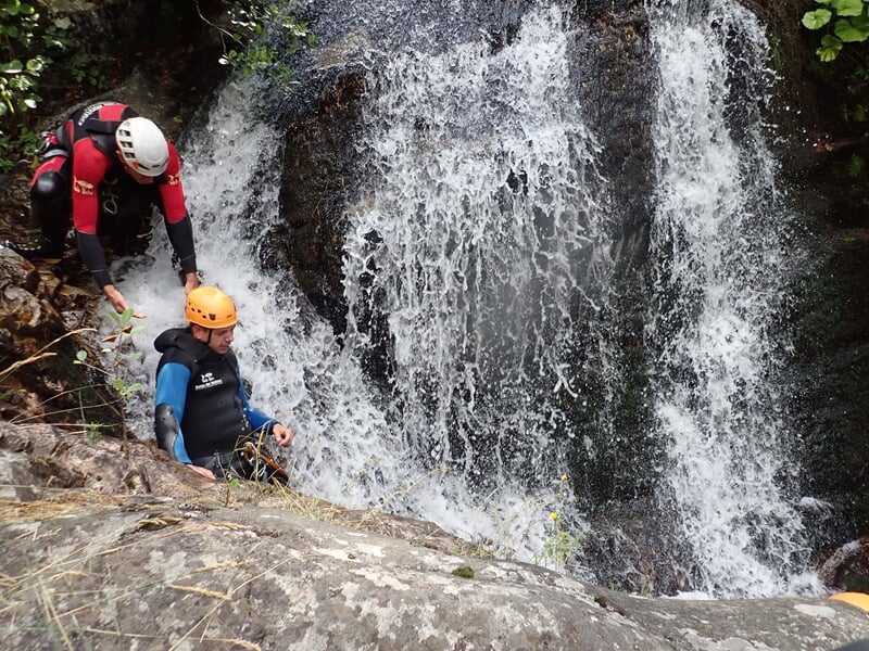 Deux personnes pratiquant le canyoning sous une cascade