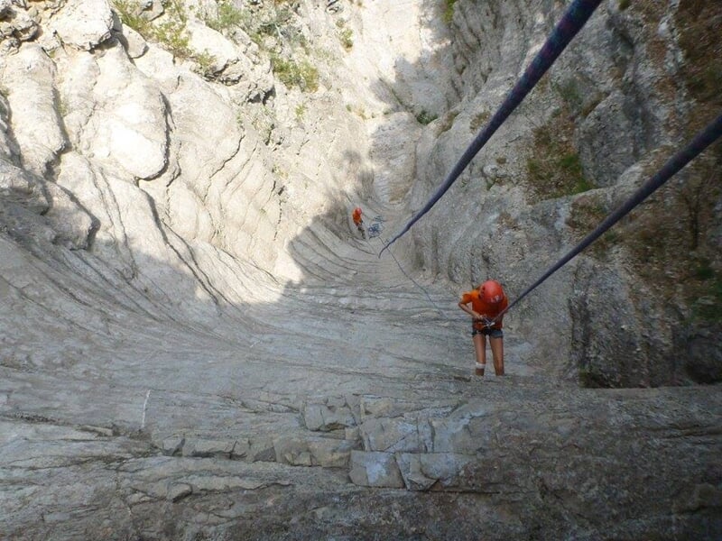 Groupe de personnes faisant du rappel dans un canyon sec