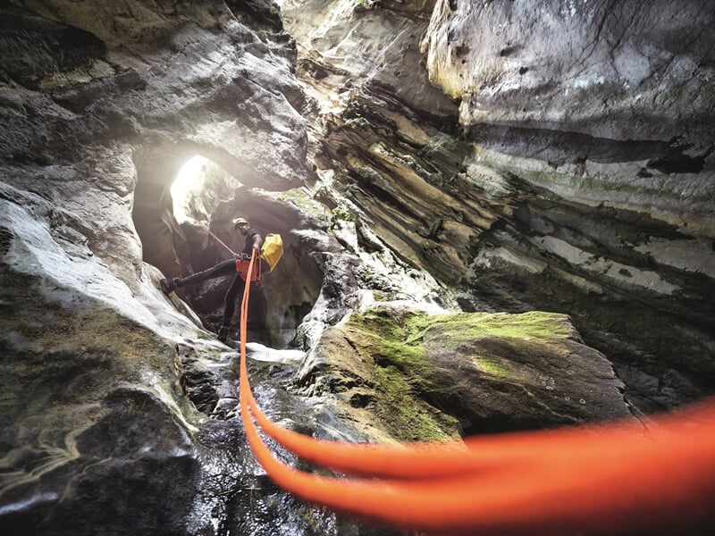 homme effectuant une descente en rappel dans un canyon sec