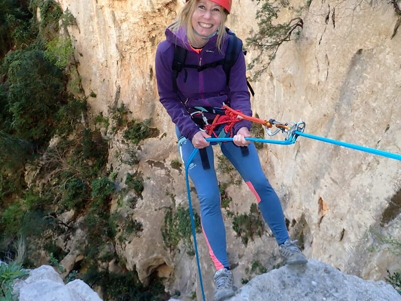 Personne effectuant une descente en rappel dans un canyon sec