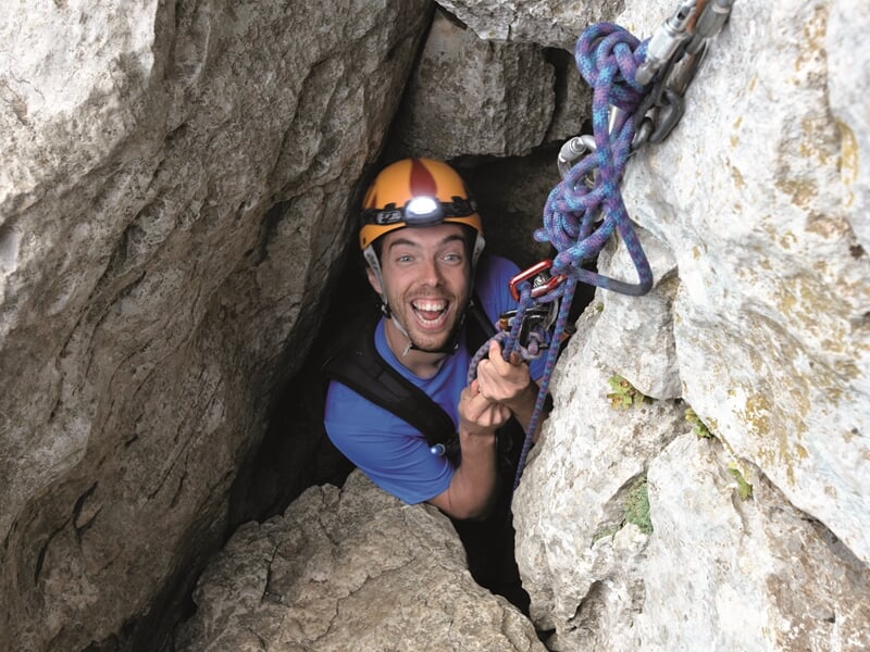 Personne pratiquant l'escalade dans un passage étroit